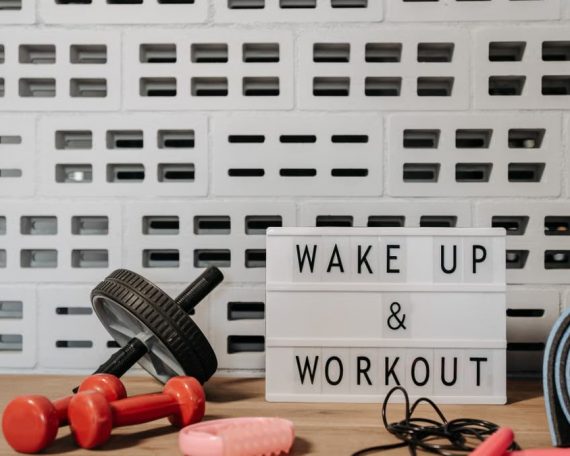 Fitness gear and motivational sign in home gym setup against a brick wall.